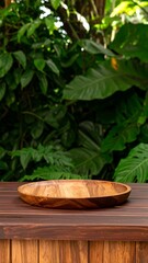 Empty wooden platter on wooden surface, tropical foliage background