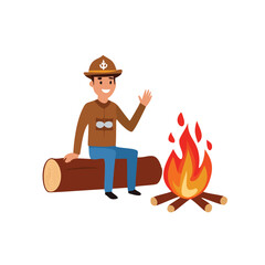 Smiling scout waving by campfire on log outdoors