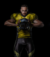 Athletic male in American football gear on dark background. Ideal for sports ads, team promotions, championship posters, training concepts, strength and motivation themes.
