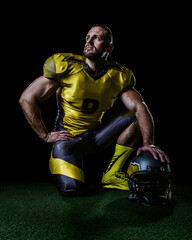 American football player in yellow uniform kneeling on field with helmet. Perfect for sports ads, motivation posters, strength concepts and team spirit promotions.