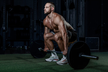 Muscular man having training with weights. Strong athletic man does workout. Concept bodybuilder doing exercises in gym.