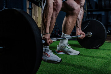 Muscular man having training with weights. Strong athletic man does workout. Concept bodybuilder doing exercises in gym.