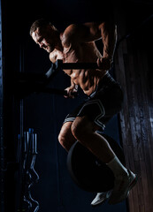 Muscular man having training with weights. Strong athletic man does workout. Concept bodybuilder doing exercises in gym.