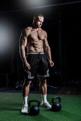 Muscular man training with weights. Brutal strong athletic men pumping up muscles workout in dark gym.