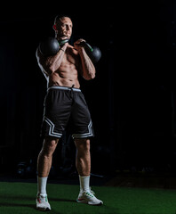 Muscular man training with weights. Brutal strong athletic men pumping up muscles workout in dark gym.