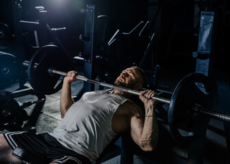 Muscular man having training with weights. Strong athletic man does workout. Concept bodybuilder doing exercises in gym.