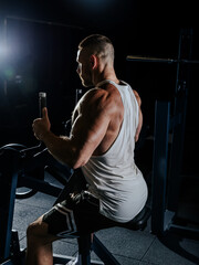 Muscular man having training with weights. Strong athletic man does workout. Concept bodybuilder doing exercises in gym.