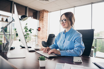 Professional woman working at her desk in a modern office space, showcasing a productive and collaborative workspace.