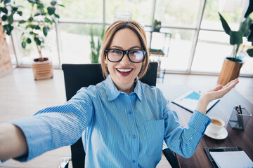 Confident businesswoman taking a selfie in a modern office setting, showcasing her professionalism...