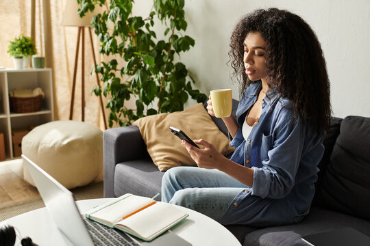 Beautiful african american woman enjoying a coffee while working from her cozy apartment - Powered by Adobe