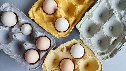 Overhead view shows fresh eggs in colorful carton containers for cooking and baking needs