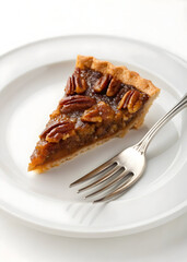 Delicious pecan pie slice served on white plate with fork ready for a sweet dessert treat