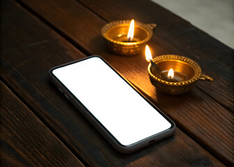 Illuminated metal oil lamps and a smartphone with a blank screen on a wooden surface