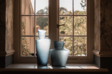 Two elegant vases on a window sill, bathed in soft natural light, dramatic light
