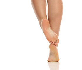 Studio shot of fat obese plus size woman legs with crossed raised foot soles posing rear view on white background.
