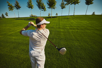 Golfer swinging club on sunny green course with trees. Concept of precision, outdoor leisure, concentration, training, fitness and sporting lifestyle. © Lustre Art Group 