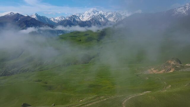 Aerial view rises over a dramatic rock crest above a deep valley at Aktoprak Pass, Kabardino-Balkaria, Russia; soft clouds and bright morning make a compelling cinematic landscape for travel content
