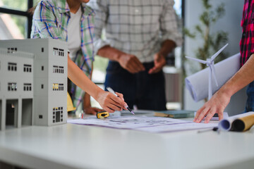 Engineers analyzing blueprints and building model for new sustainable project