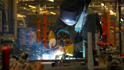 Welder in protective gear working in a factory with sparks flying. Ideal for industry, labor, manufacturing, metalwork, and occupational safety themes.