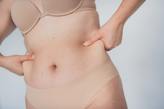 Young woman embracing body positivity in natural lingerie showcasing beauty and confidence on a white background
