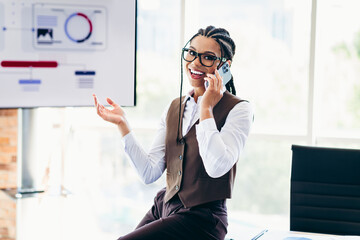 Professional businesswoman in formalwear with braided hairstyle speaking on the phone during a corporate office presentation