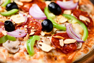 Pizza with chorizo ​​sausage, mozzarella cheese, green pepper and black olives. Rustic wooden background. Soft focus.	