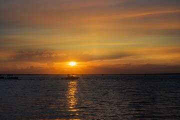 Fototapeta premium Serene sunset with silhouetted boat on ocean.
