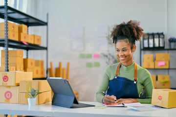 Young african american woman entrepreneur managing her online business taking notes from tablet