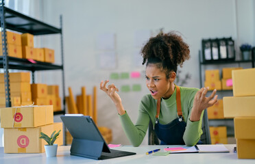 Stressed young african american woman managing online orders in warehouse