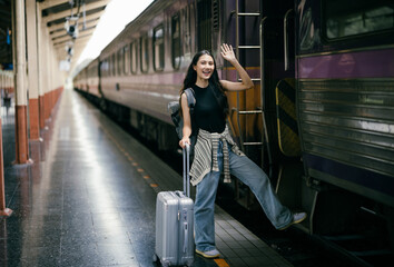 Young woman waving goodbye while boarding a train at the station