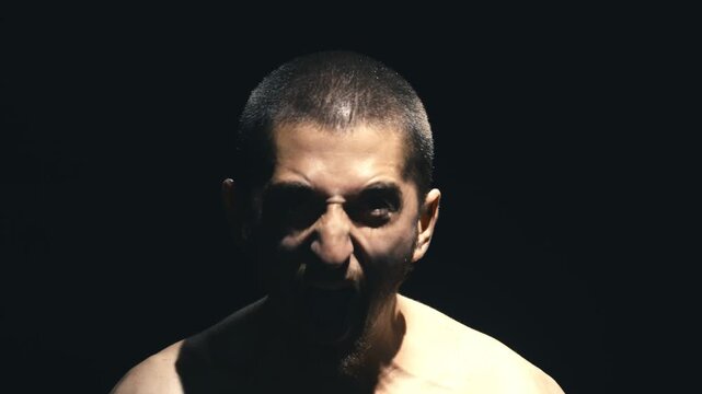 Intense male figure with short hair transitions from calm to fierce expression, showcasing emotional evolution and raw energy in a dramatic lighting setup