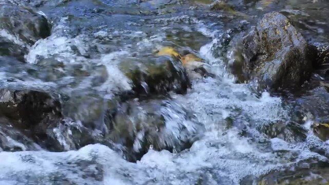 Fast flowing river water and boulders. Jamor River - Rio Jamor, Oeiras, Portugal.