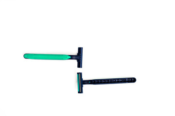 Two disposable razors, one with a green handle and one with a black handle, on white