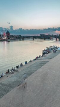 Aerial view of Port de la Daurade park along the Garonne River day to night transition timelapse in Toulouse, France. La Grave Hospital with Saint-Pierre Bridge during sunset with colorful clouds