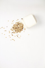 Scattered Coriander Seeds from a White Container on a Clean White Background