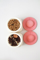 Overhead view of spices in white jars with matching pink lids on white background