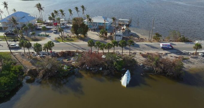 Capsized sunken sailing boat left forsaken on shallow bay waters after hurricane Milton in Englewood, Florida.