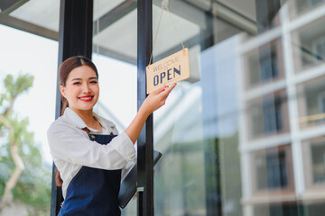 Smiling waitress hanging open sign on glass door of coffee shop