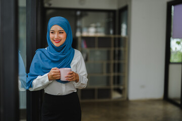 Muslim businesswoman drinking coffee during break in office