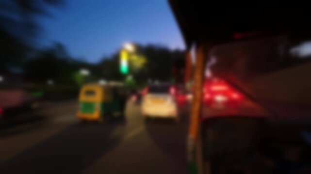 Blurred view from the cabin of an autorickshaw in Delhi, India. Bokeh time lapse motion video of the city roads with vehicle traffic in the evening.