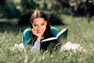Young woman enjoying a book while relaxing on grass in a peaceful park, embodying education, happiness, and outdoor leisure