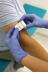 Obraz premium Medical professional applying white tourniquet on patient’s arm before blood draw.