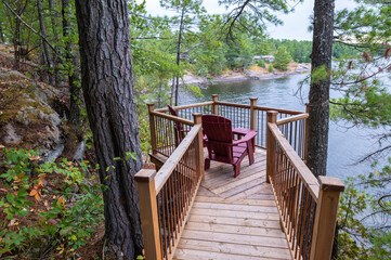 Two Red Adirondack Chairs on a Deck Overlooking French River in Ontario Cottage Country