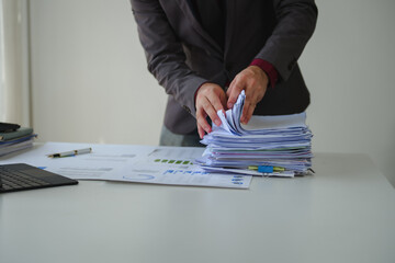 Businessman searching through stack of paperwork at office desk