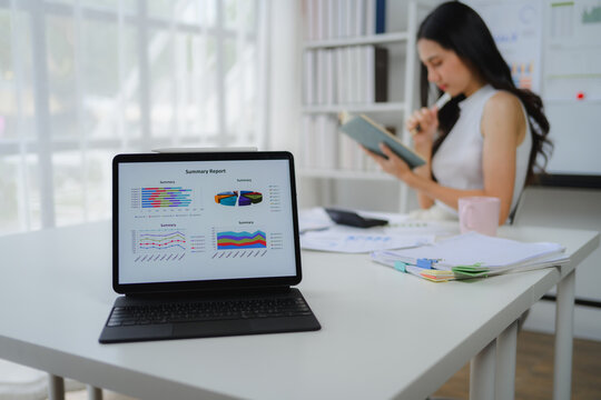 Businesswoman analyzing summary report on tablet with charts and graphs
