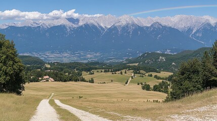Panoramic vista of a valley with a dirt road, mountains, and a rainbow
