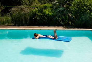 Pretty young woman lounging on her mattress in the middle of the water