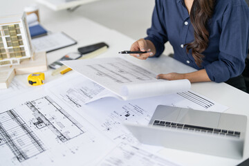 Asian woman engineer designs plans in an office with blueprints