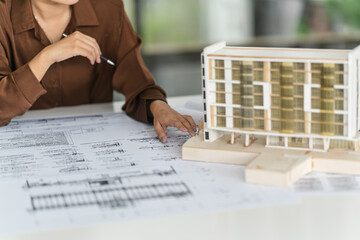 Asian woman engineer reviewing blueprints for projects in office workspace