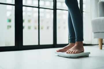 Close up woman bare feet standing on digital electronic scales at home, loss weight concep